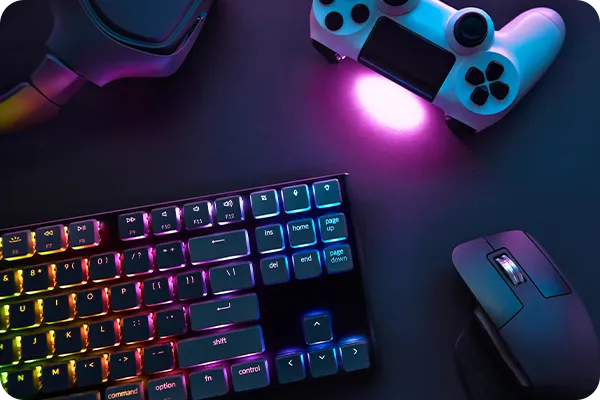 Kit gamer com teclado iluminado, mouse e controle sobre superfície escura.