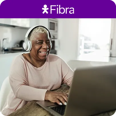 Mulher de camiseta rosa, com fones de ouvido usando notebook em uma cozinha moderna