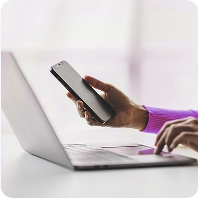 Imagem de mãos segurando celular enquanto digita em notebook