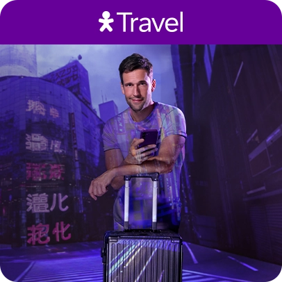 Imagem de pessoa segurando celular e apoiado em uma mala de viagem, no fundo um cenário turístico