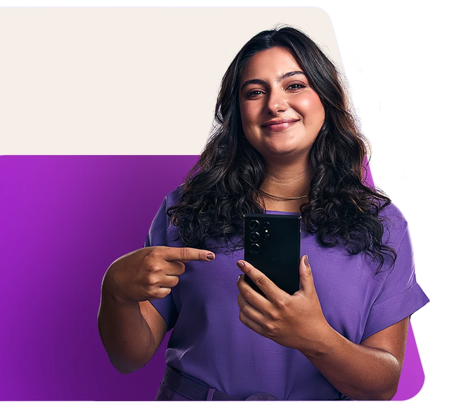 Imagem de uma mulher sorrindo, apontando para o celular que está segurando.