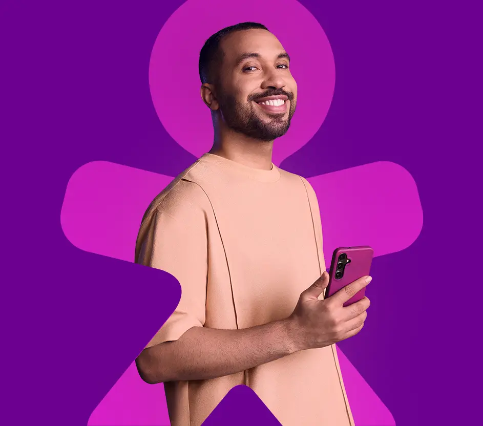 Gil do Vigor sorrindo com um celular roxo na mão dentro do Vivinho em fundo roxo.