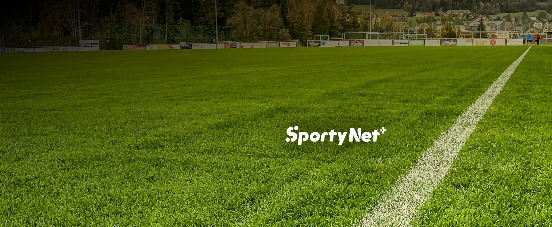 Logotipo do SportyNet+ sobre gramado de campo de futebol com marcação lateral.