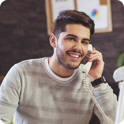 Homem sorrindo falando no telefone fixo.
