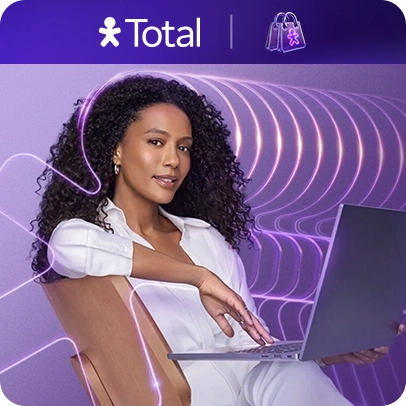 Tais Araújo sentada em uma cadeira, segurando o notebook com logo Vivo Total e sacolinha em cima.