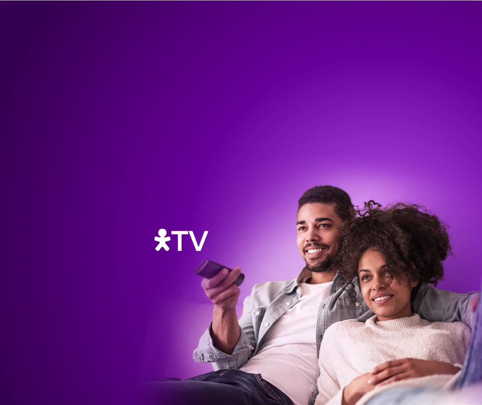 Casal deitado em um sofá com controle na mão e logo Vivo TV do lado.