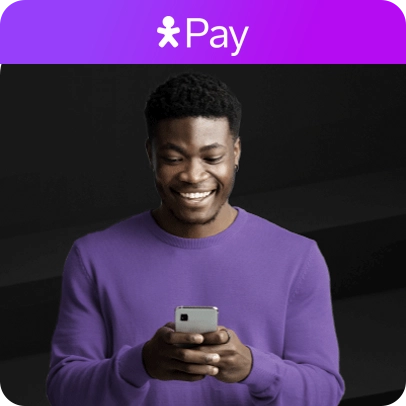 Jovem sorrindo, usando camiseta roxa e celular, sobre fundo escuro.