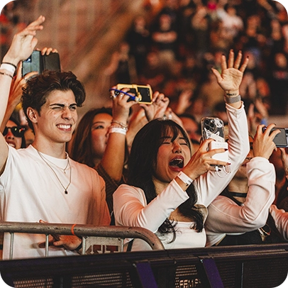 Público em show com mãos levantadas e celulares registrando o momento.