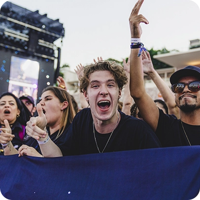 Show ao ar livre com público animado e palco iluminado ao fundo.