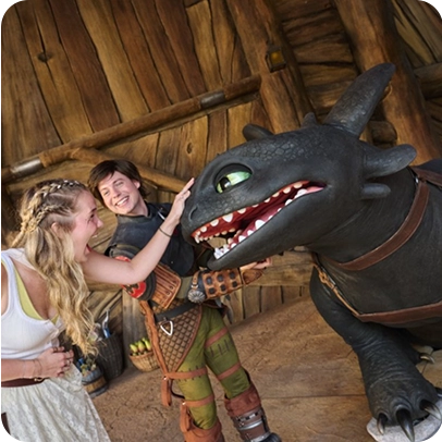 Pessoas ao lado de dragão animatrônico em cenário temático do Universal Epic Universe.