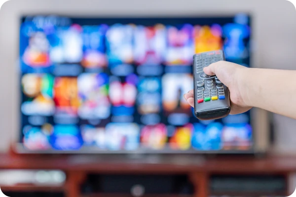 Pessoa utiliza controle remoto para acessar conteúdos em Smart TV conectada.