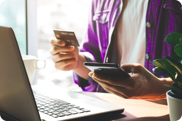 Pessoa utiliza smartphone e cartão para realizar compra online.