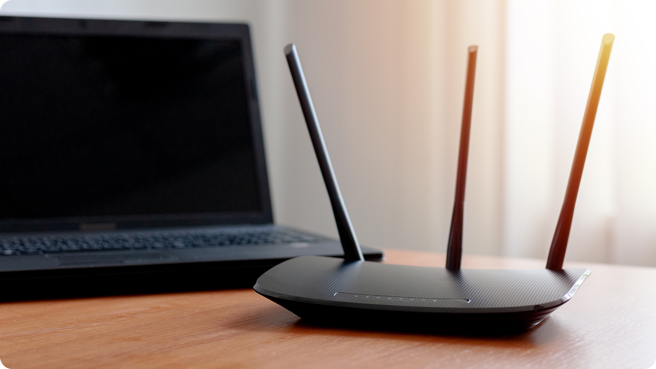 Roteador Wi‑Fi ao lado de notebook representa conexão de internet por IP.