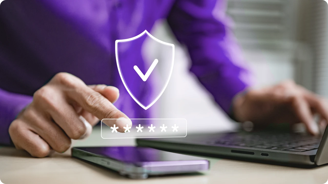  Pessoa utiliza notebook e smartphone com representação de proteção por senha.