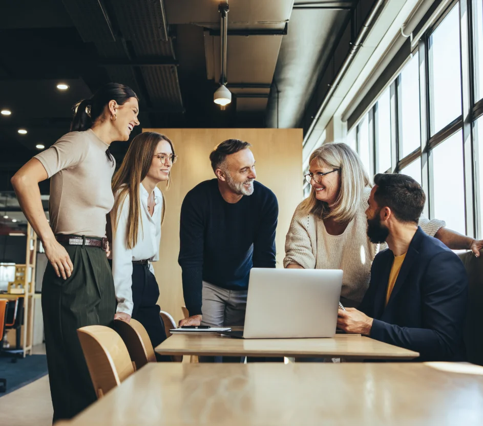 Pessoas conversando ao redor de uma mesa com notebook no trabalho