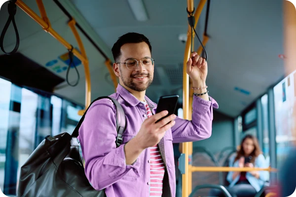 Pessoa em ônibus acessa serviços digitais pelo celular durante deslocamento.