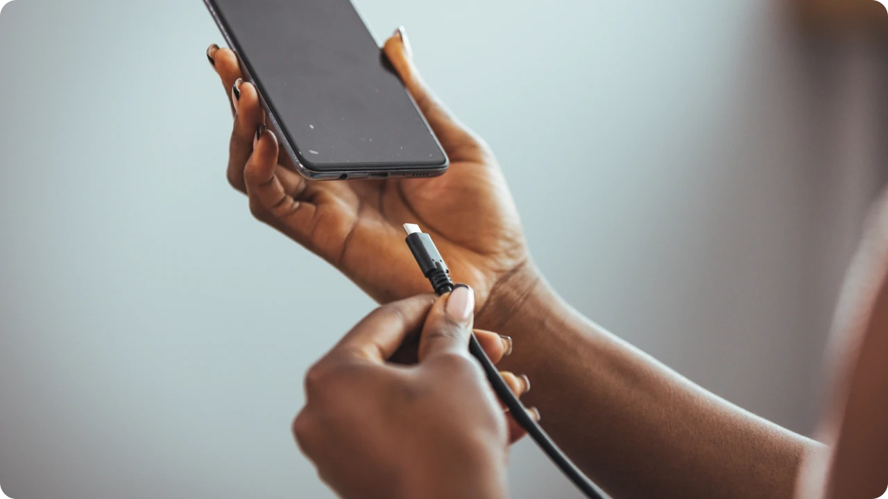 Pessoa aproxima cabo USB-C de smartphone para realizar carregamento.