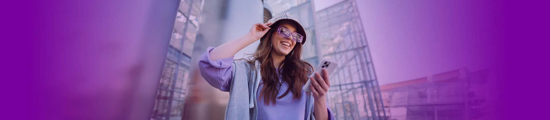 Imagem de uma menina sorrindo de chapéu com um celular na mão