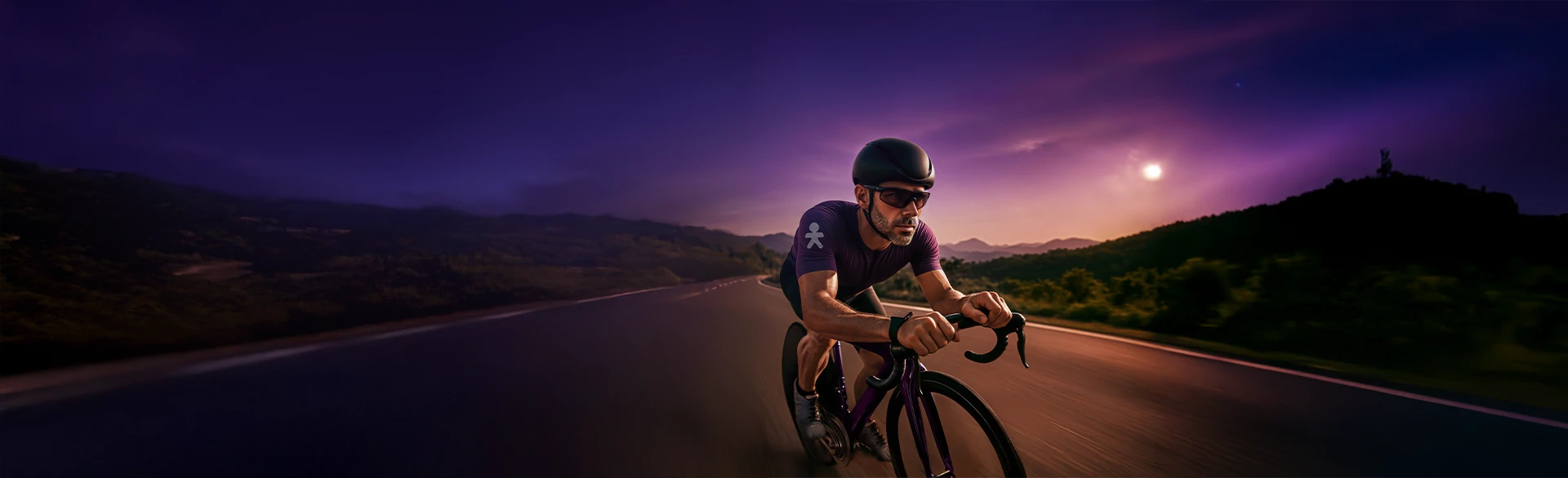 Homem andando de bicicleta com roupa esportiva e capacete em uma estrada.