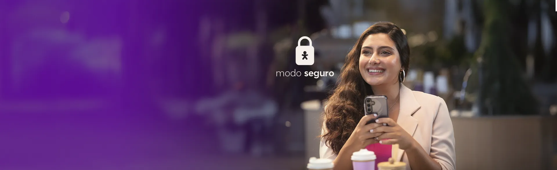 Mulher sentada sorridente com um celular nas mãos.