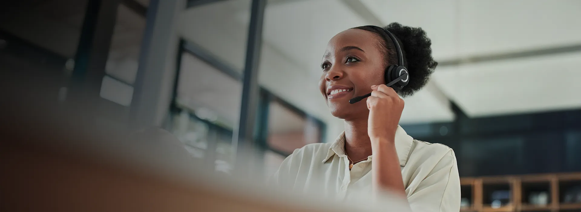 Imagem de uma mulher com camiseta branca sorrindo com um fone de ouvido com microfone