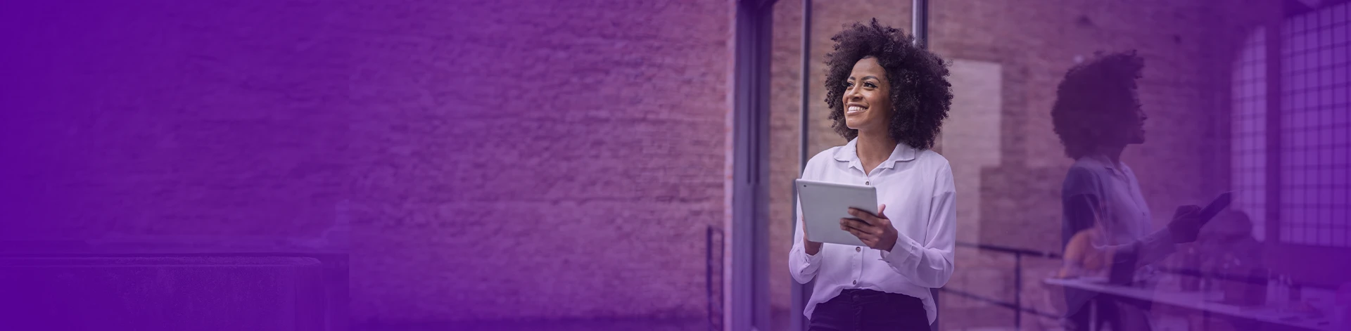 Mulher empresarial com um tablet na mão sorrindo em um ambiente externo de um escritório.