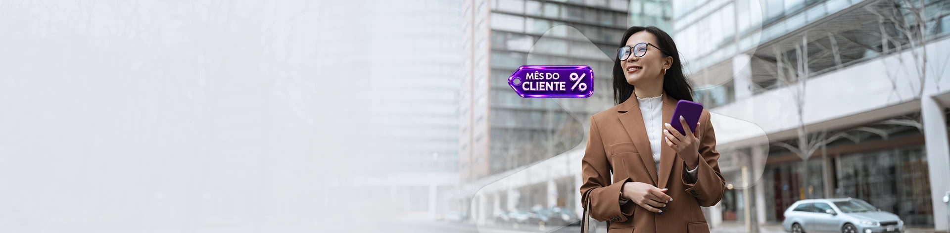 Mulher com blazer, sorrindo e segurando celular, ao lado selo da campanha Mês do Cliente.