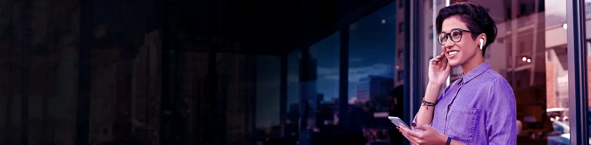 Pessoa utilizando smartphone e fones em ambiente corporativo com foco em conectividade.