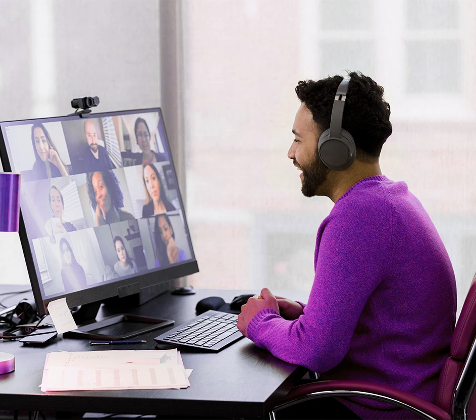 Imagem de uma pessoa sentada no computador fazendo uma reunião remota com outras pessoas.