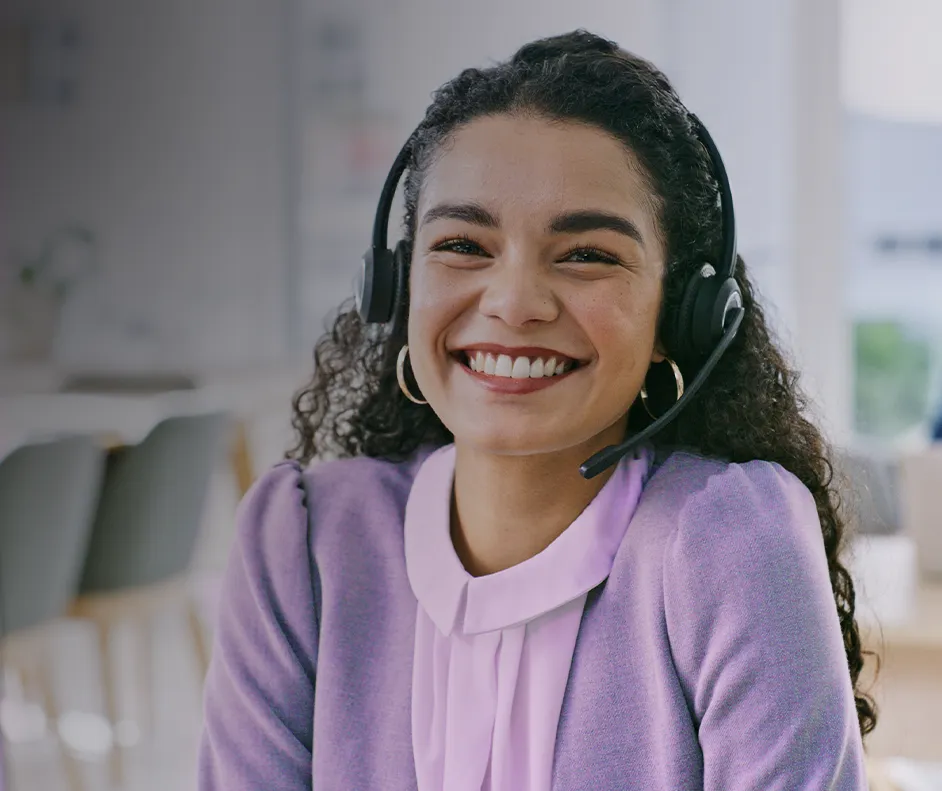 Imagem de uma mulher sorrindo com uma blusa roxa e fone de ouvido com microfone