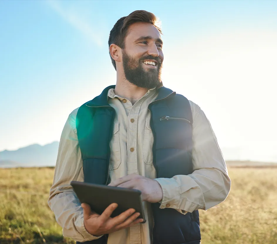 Imagem de um fazendeiro em um pasto com um tablet nas mãos