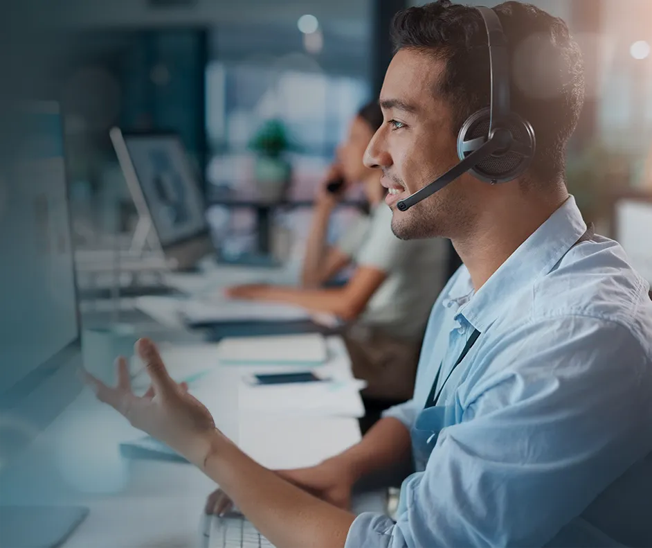 Imagem de um homem sentado em uma mesa de frente pro computador com um fone de ouvido e microfone