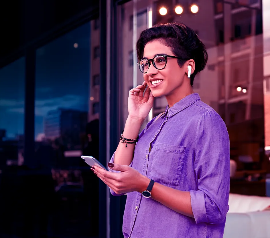 Imagem de uma mulher com fones de ouvido e celular na mão falando ao telefone