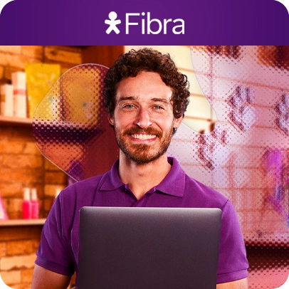 Homem sorrindo de camiseta roxa segurando notebook em ambiente comercial, lê-se "Vivo Fibra".
