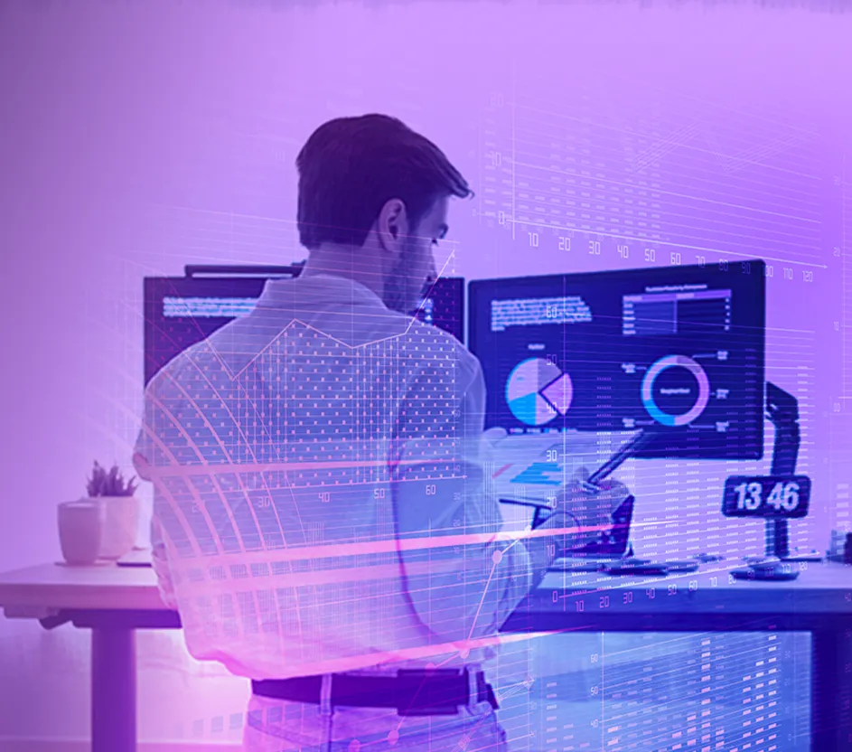 Homem de costas lendo um relatório a frente de uma mesa de computador com gráficos na tela.