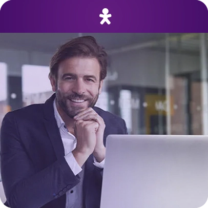 Imagem de uma pessoa sorrindo e sentada em frente ao computador