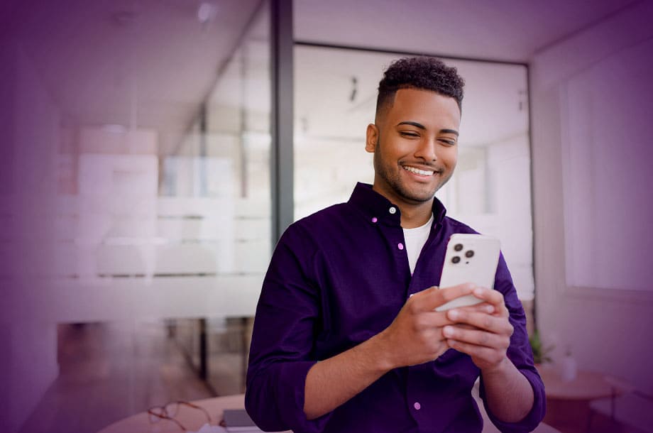 Imagem de um homem sorrindo usando celular.