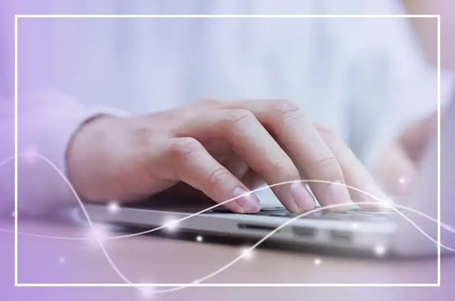 Mãos digitando em um teclado de notebook. Fundo com tons claros e efeitos luminosos.