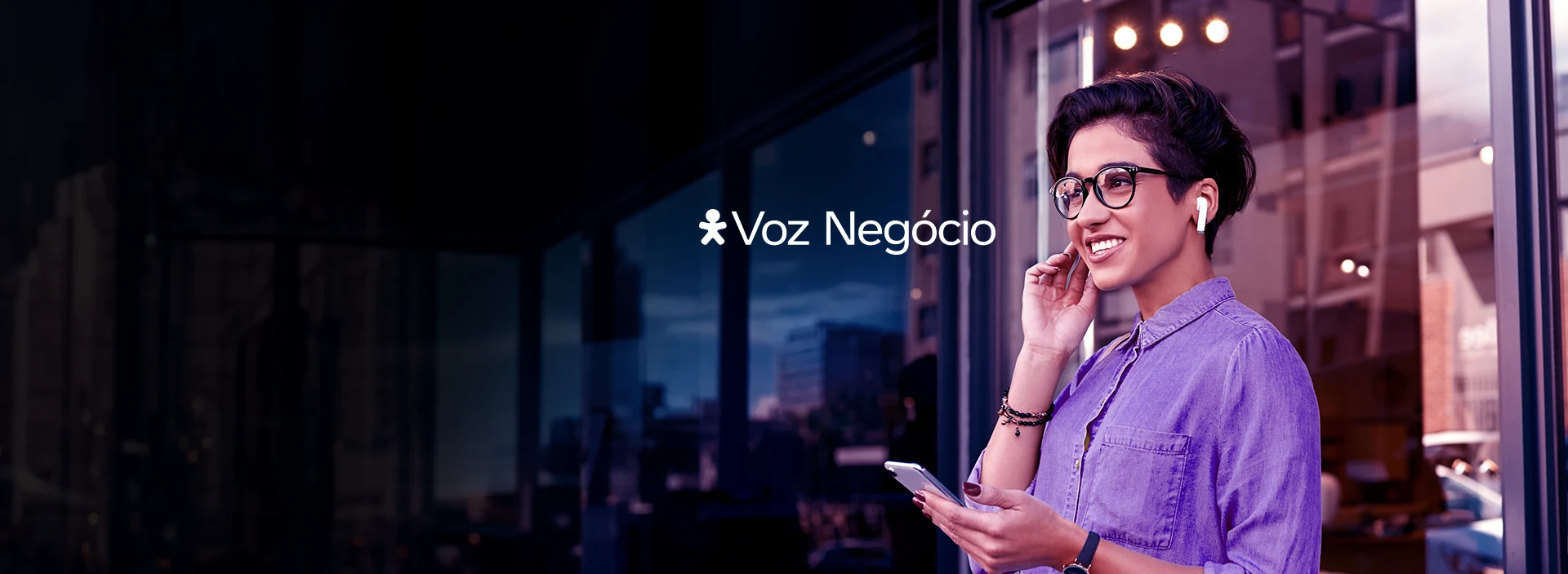 Mulher sorrindo com celular na mão e usando fones de ouvido com logo Vivo Voz Negócio em cima.